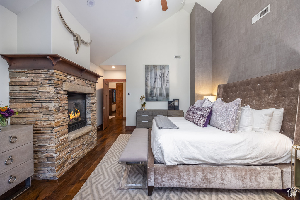 Bedroom with ceiling fan, a stone fireplace, high vaulted ceiling, and dark wood-type flooring