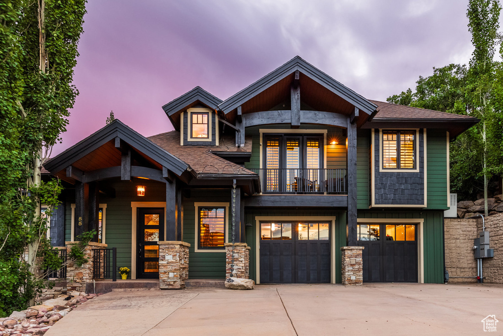 View of front of home featuring a garage and a balcony