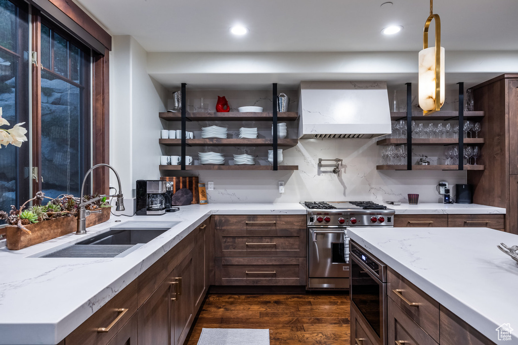 Kitchen with custom exhaust hood, dark hardwood / wood-style flooring, sink, dark brown cabinetry, and appliances with stainless steel finishes