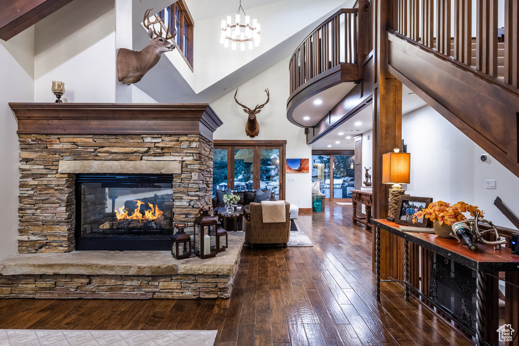 Living room featuring a fireplace, a notable chandelier, dark hardwood / wood-style flooring, and a high ceiling