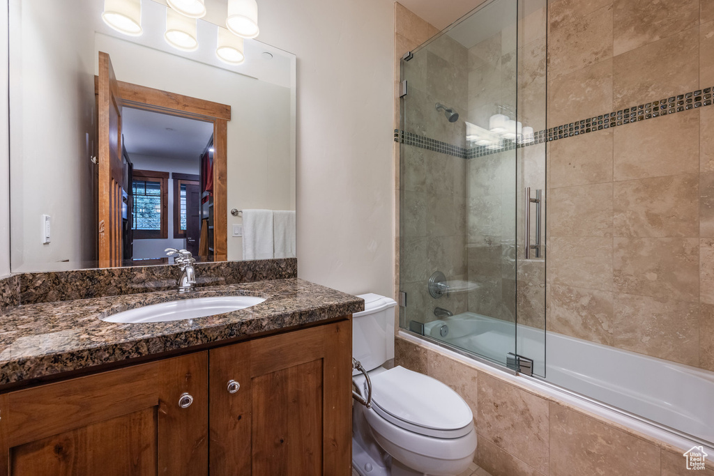 Full bathroom with vanity, combined bath / shower with glass door, and toilet