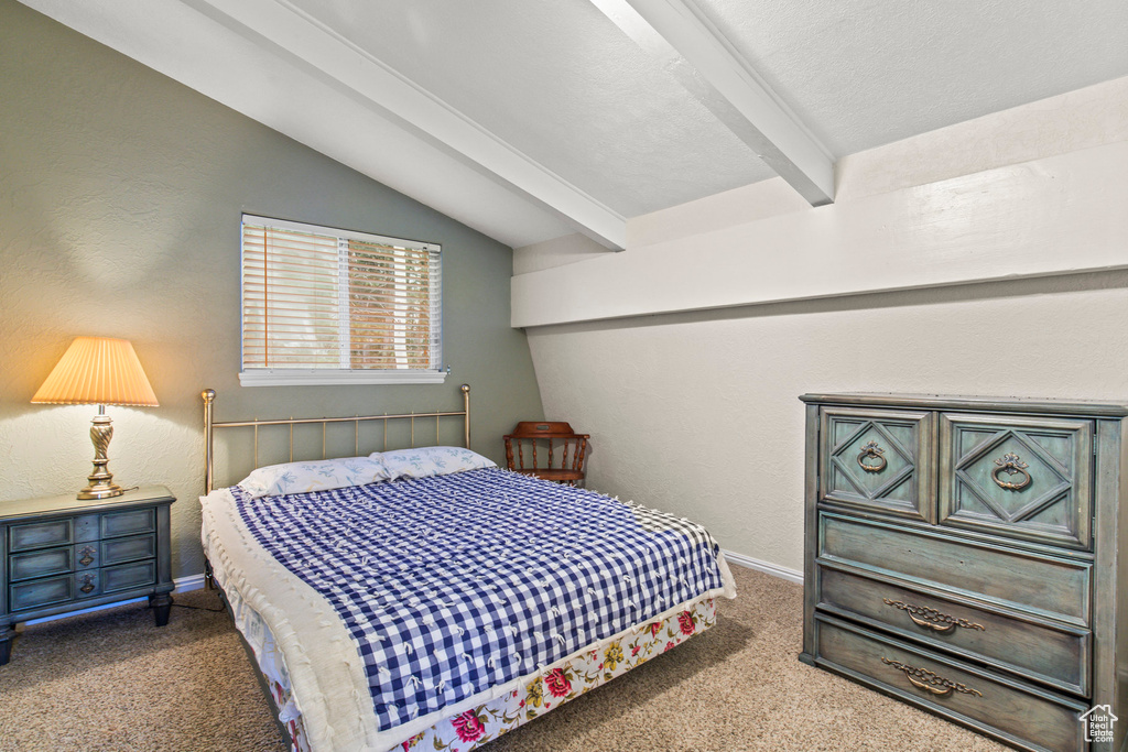 Carpeted bedroom featuring lofted ceiling with beams and a textured ceiling