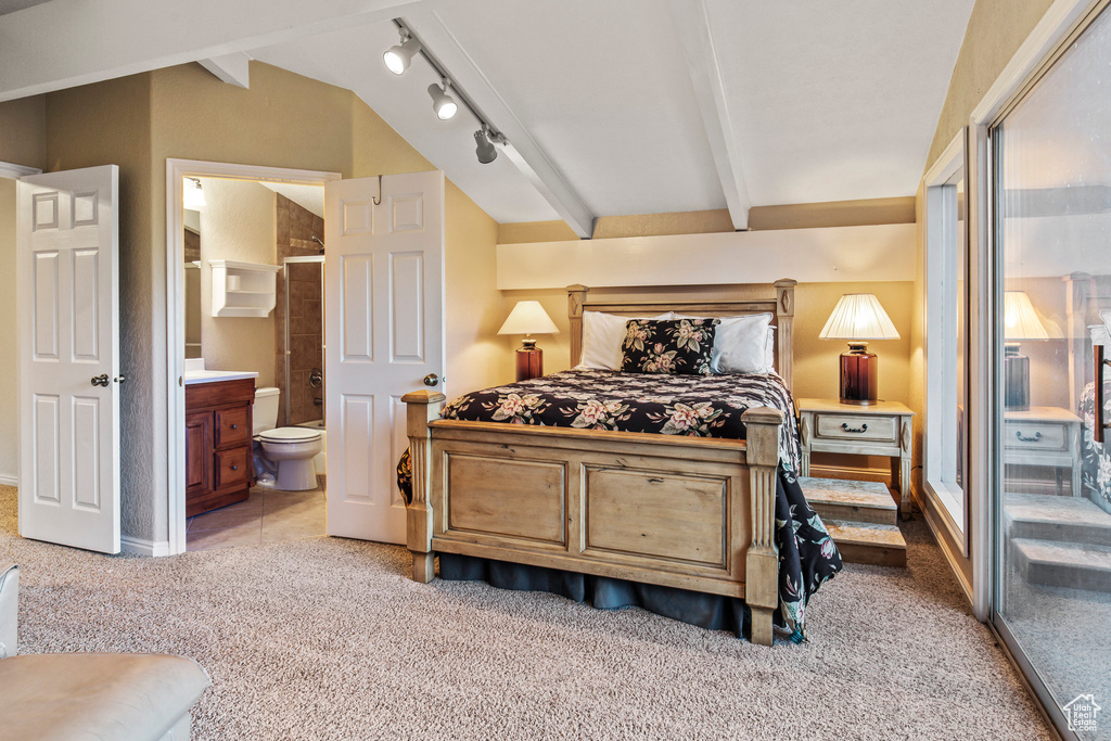 Bedroom with carpet flooring, track lighting, vaulted ceiling with beams, and ensuite bathroom