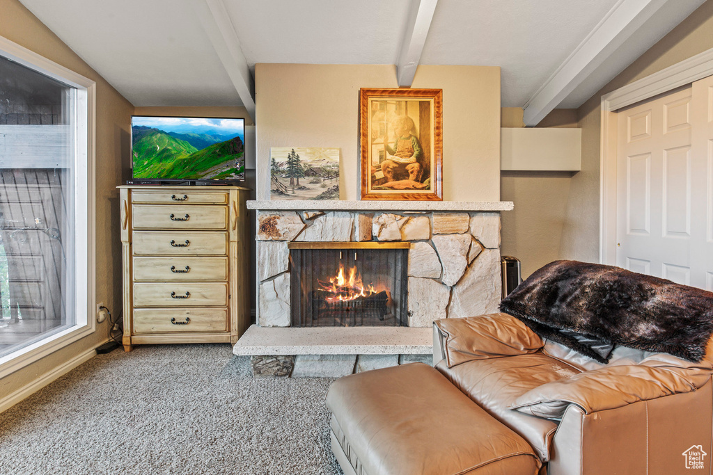 Carpeted living room with vaulted ceiling with beams and a fireplace