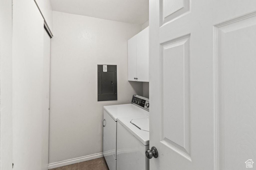 Laundry area with tile patterned flooring, electric panel, washer and clothes dryer, and cabinets