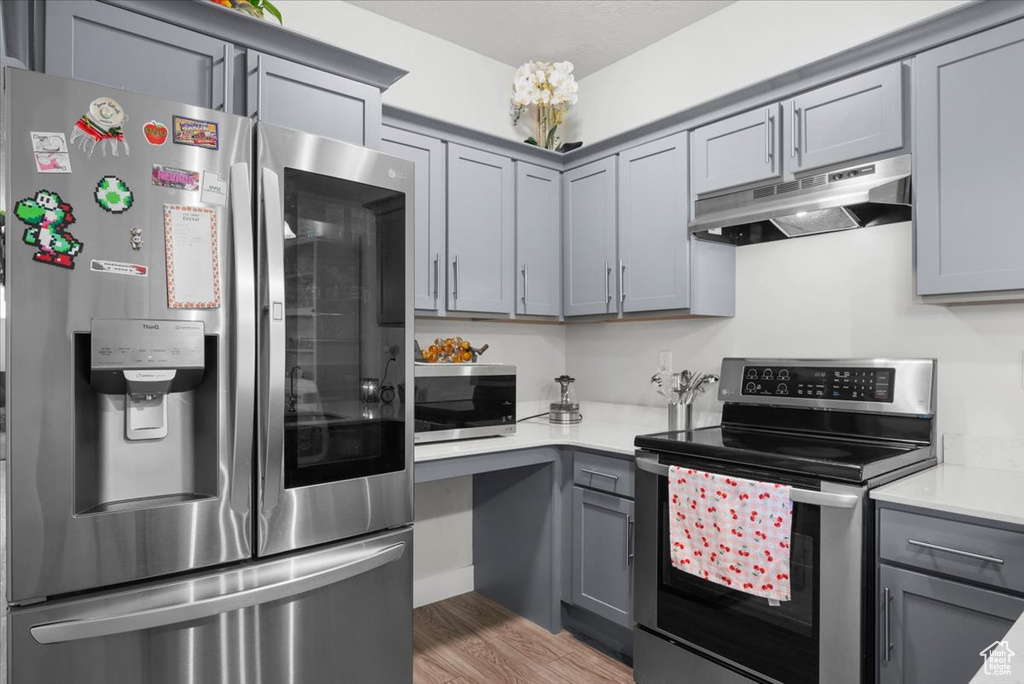 Kitchen with hardwood / wood-style flooring, stainless steel appliances, and gray cabinetry