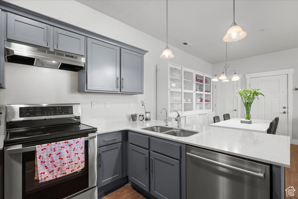 Kitchen featuring dark hardwood / wood-style flooring, stainless steel appliances, pendant lighting, sink, and gray cabinetry