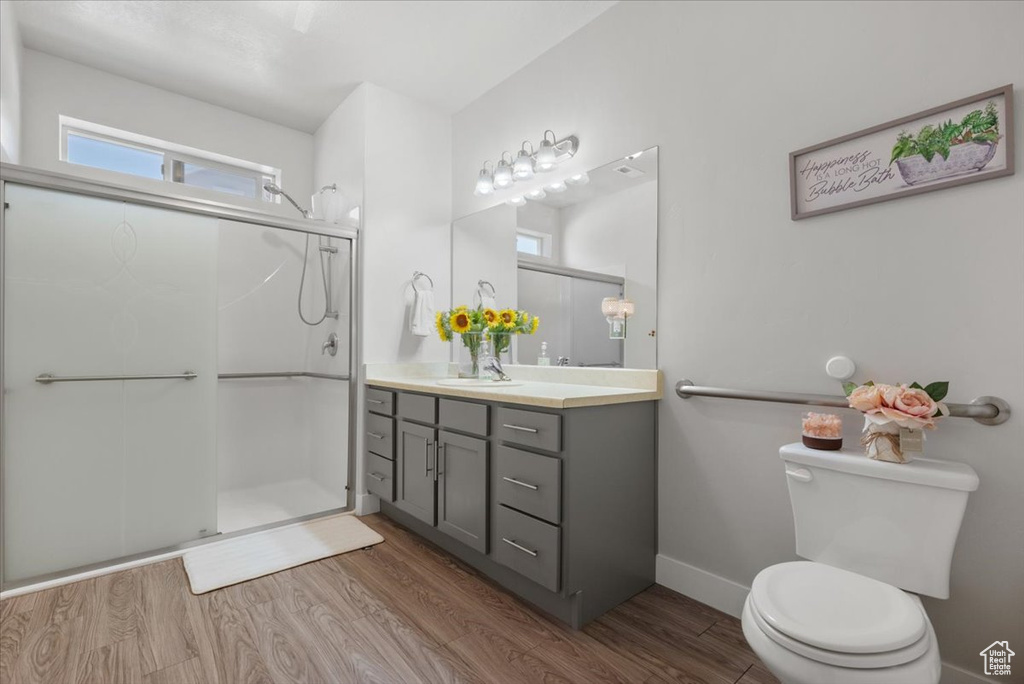 Bathroom with a shower with door, vanity, toilet, and hardwood / wood-style floors