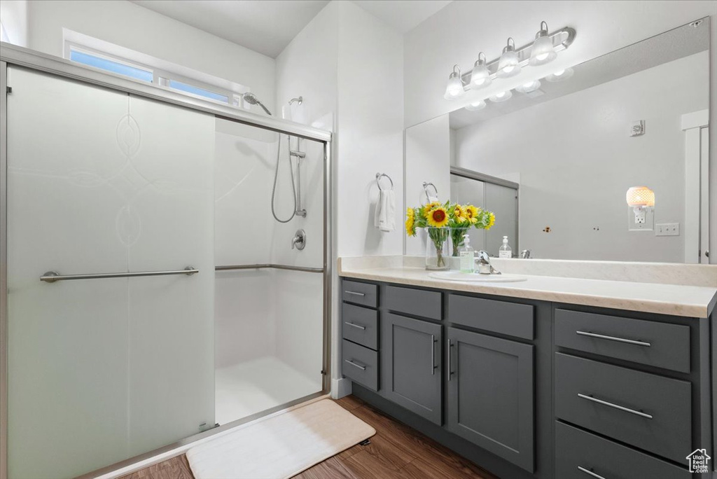 Bathroom featuring a shower with door, hardwood / wood-style floors, and vanity