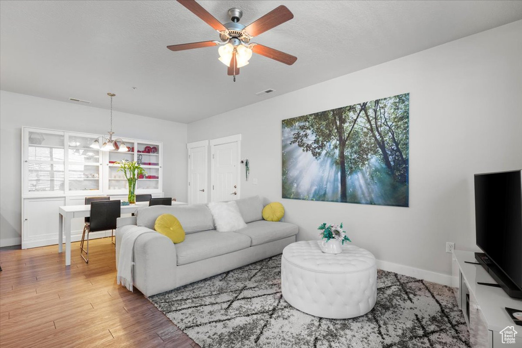 Living room featuring plenty of natural light, ceiling fan with notable chandelier, and hardwood / wood-style flooring