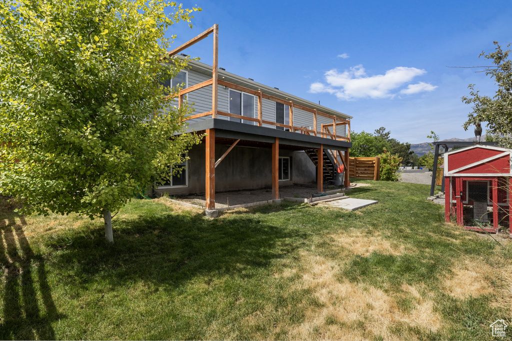 Back of house featuring a yard, a wooden deck, and an outdoor structure