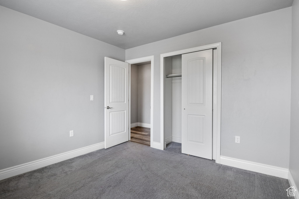 Unfurnished bedroom featuring dark colored carpet and a closet