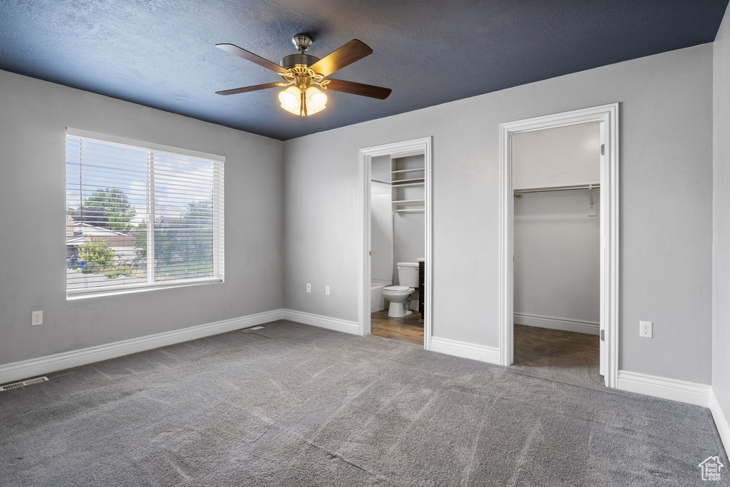 Unfurnished bedroom with carpet flooring, ensuite bathroom, and ceiling fan