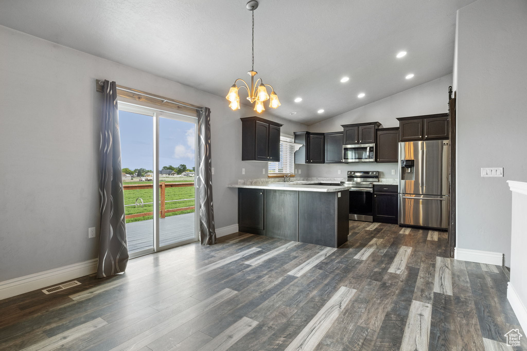 Kitchen featuring dark brown cabinetry, dark hardwood / wood-style floors, stainless steel appliances, and vaulted ceiling