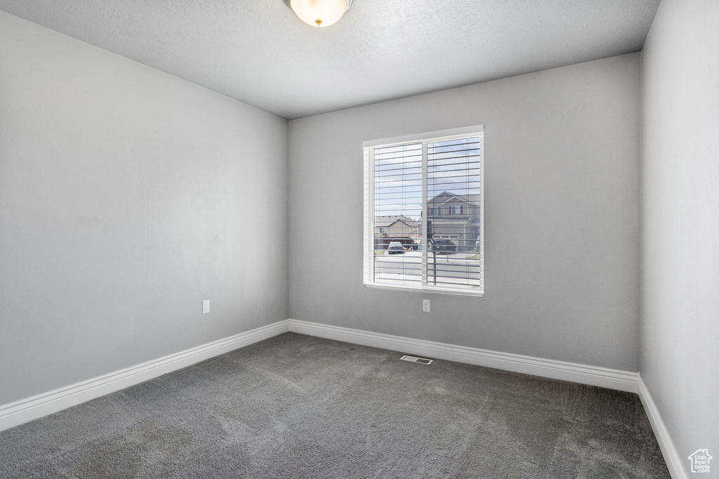 Empty room featuring dark colored carpet