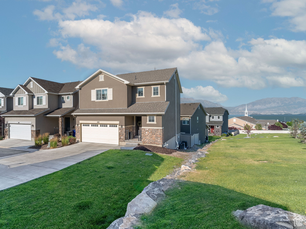 View of front facade with a garage, a front lawn, and a mountain view