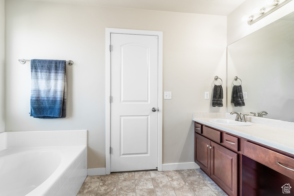 Bathroom with a relaxing tiled tub, vanity, and tile patterned floors