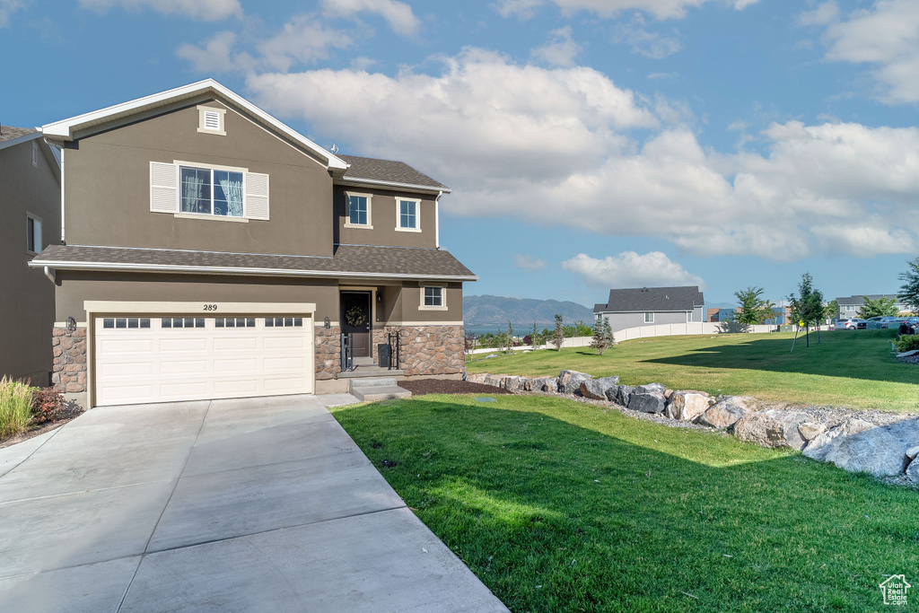 View of front of house featuring a garage, a mountain view, and a front yard