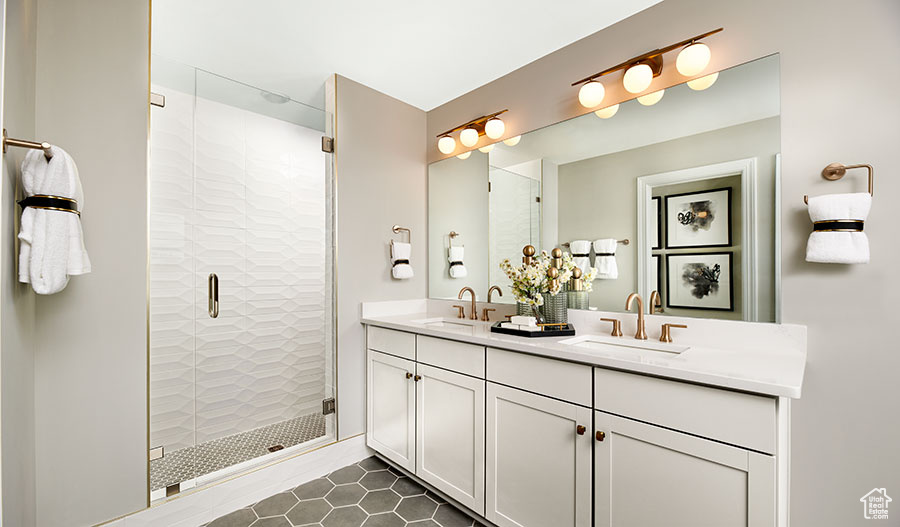 Bathroom featuring tile patterned flooring, double sink vanity, and a shower with door