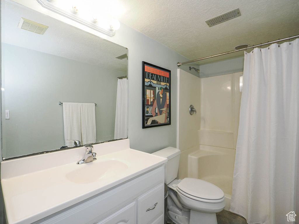 Bathroom with toilet, vanity, and a textured ceiling