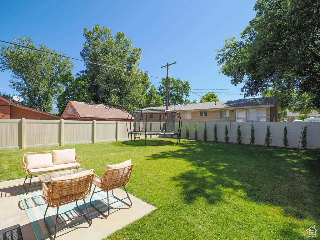 View of yard featuring a trampoline and a patio area