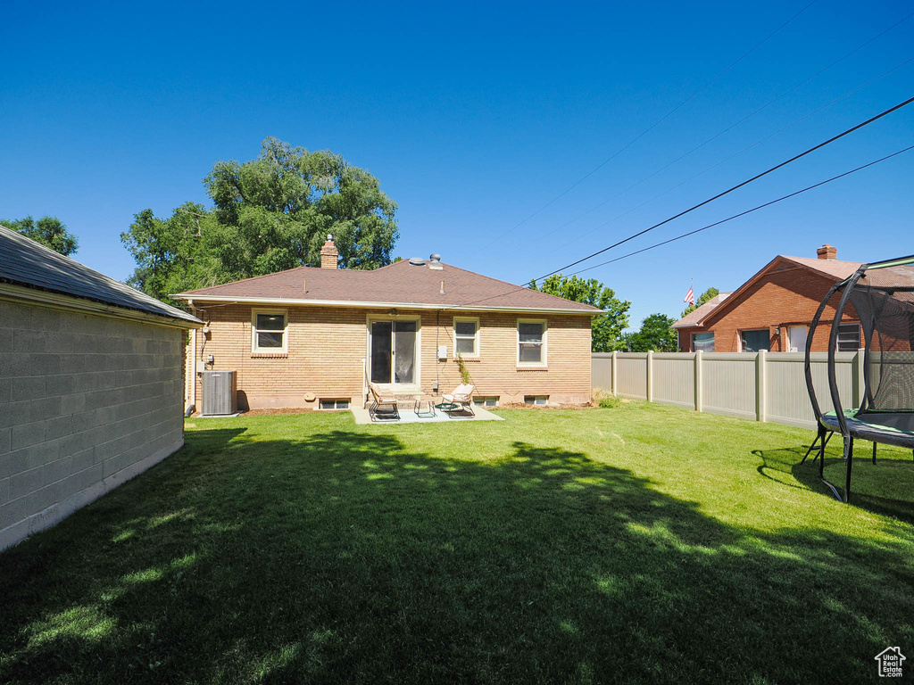 Rear view of house featuring a trampoline and a yard