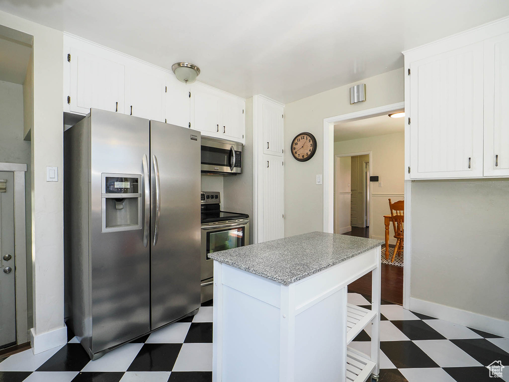 Kitchen featuring white cabinetry, dark tile patterned flooring, and stainless steel appliances