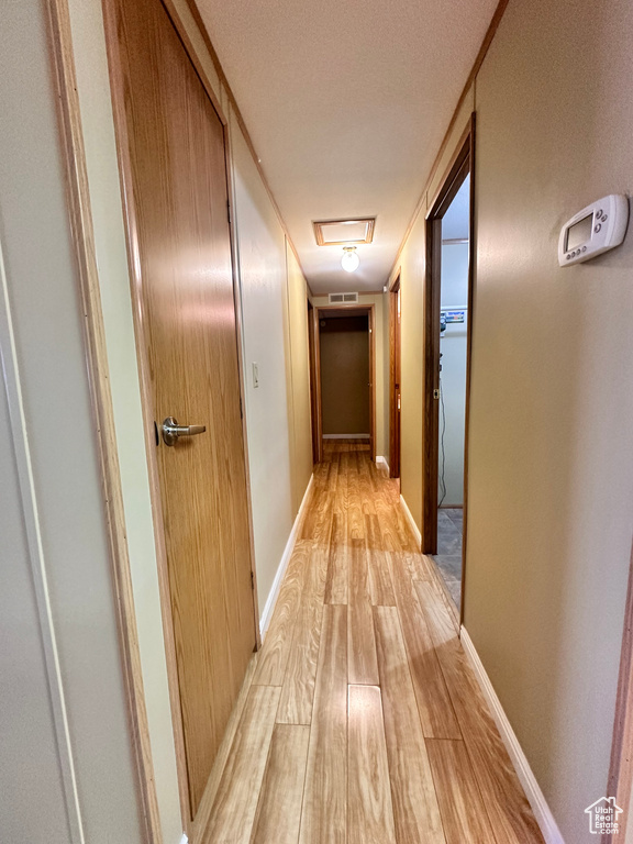 Hallway with light hardwood / wood-style flooring and a textured ceiling