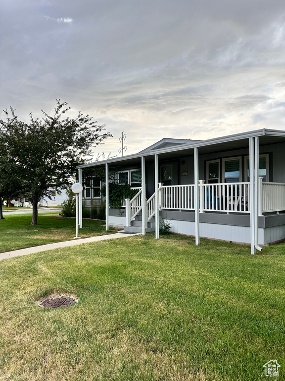 Manufactured / mobile home featuring a porch and a front lawn