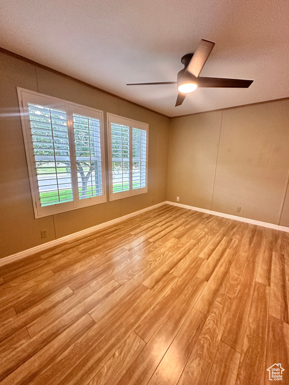 Spare room featuring light wood-type flooring, ceiling fan, and a textured ceiling