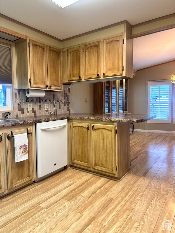 Kitchen with backsplash, dishwasher, lofted ceiling, and light wood-type flooring