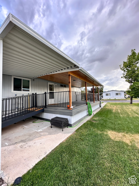 View of property exterior featuring a wooden deck and a lawn