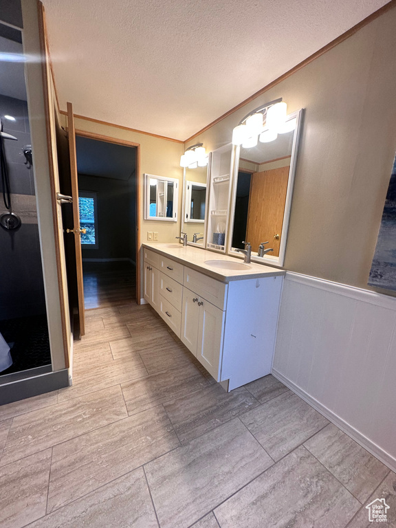 Bathroom featuring crown molding, tile patterned floors, double sink vanity, and a textured ceiling