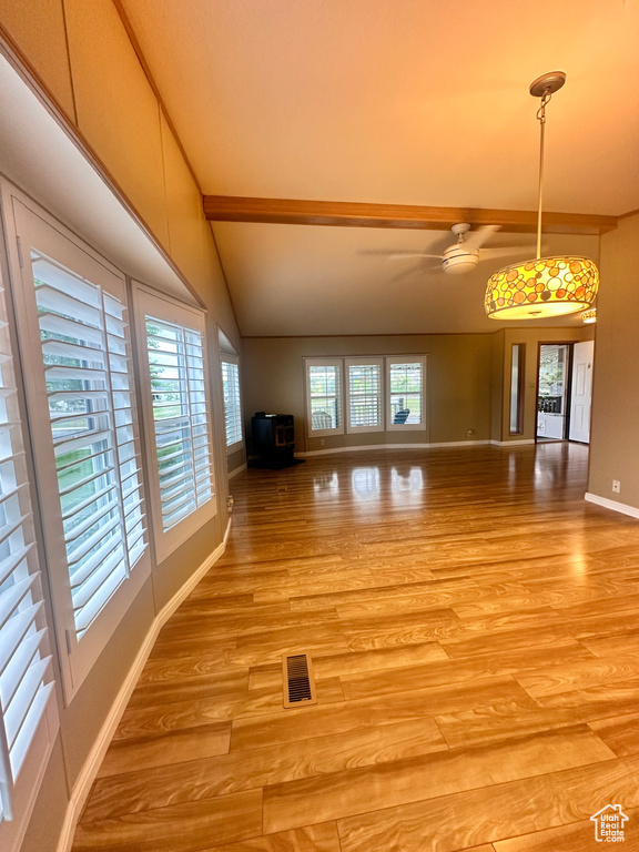 Unfurnished living room featuring light hardwood / wood-style floors and vaulted ceiling with beams