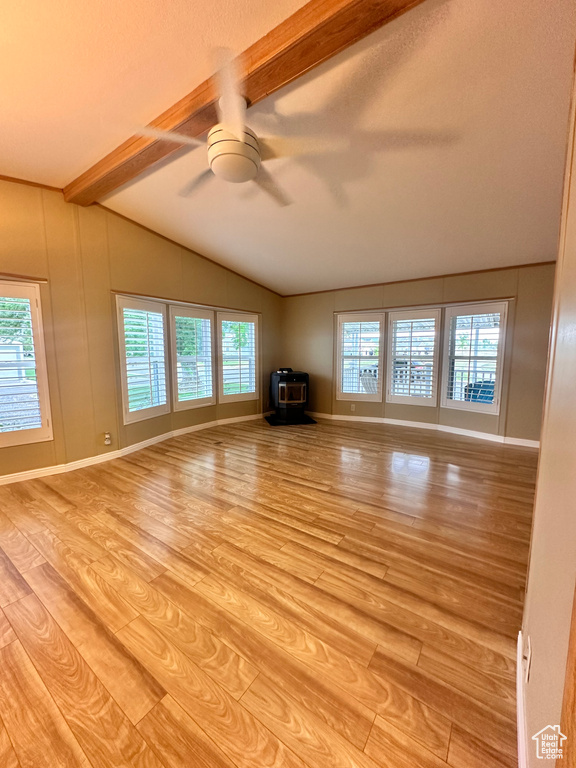 Unfurnished living room with a wood stove, vaulted ceiling with beams, light wood-type flooring, and ceiling fan