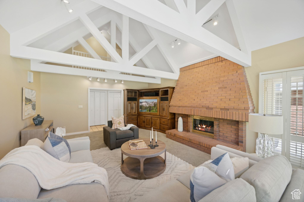 Living room featuring high vaulted ceiling, brick wall, a brick fireplace, and beam ceiling