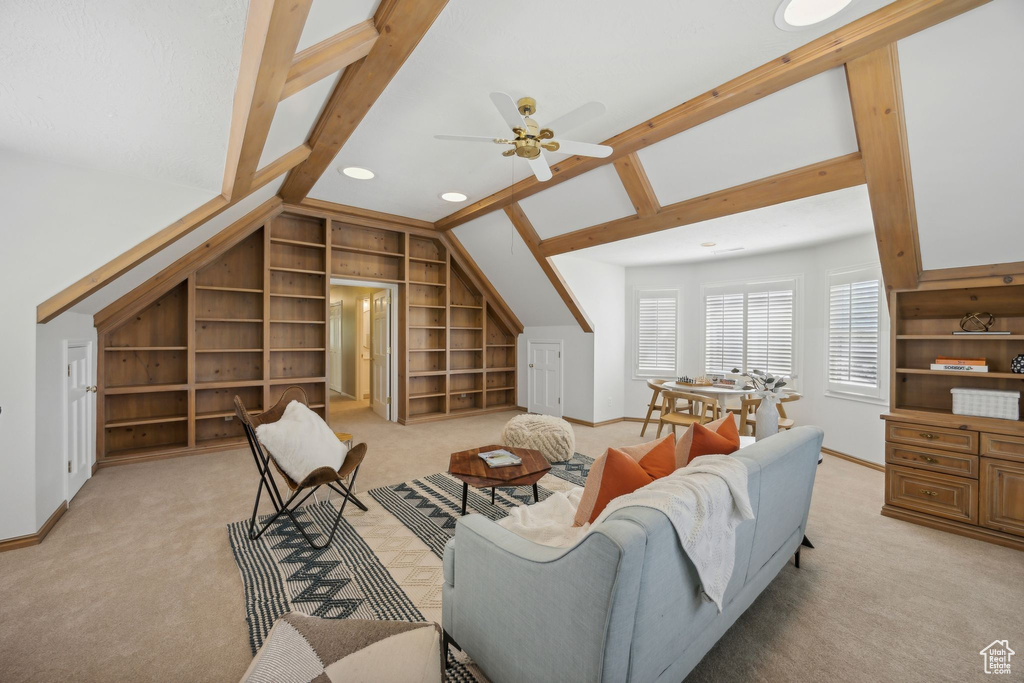 Carpeted living room featuring built in shelves, lofted ceiling, and ceiling fan