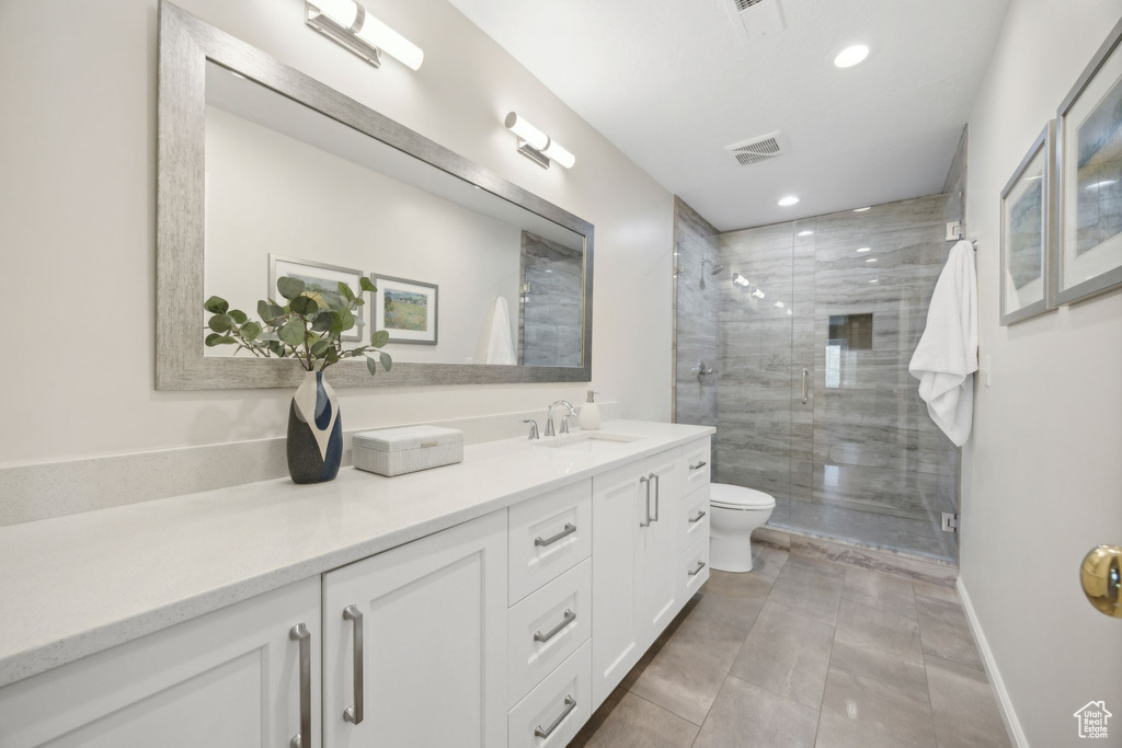 Bathroom with tiled shower, tile patterned flooring, toilet, and vanity