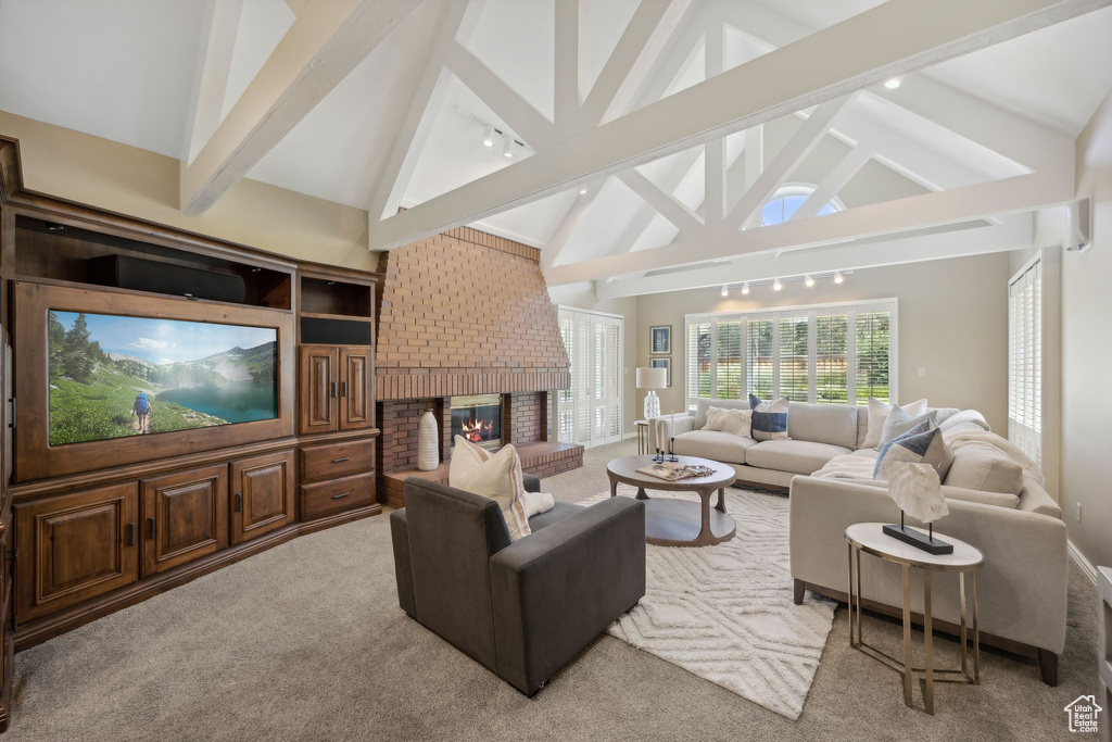 Carpeted living room with beamed ceiling, a fireplace, and high vaulted ceiling