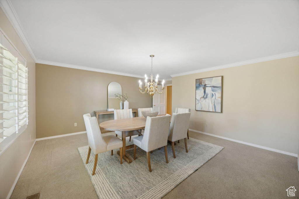 Carpeted dining space featuring an inviting chandelier, crown molding, and plenty of natural light