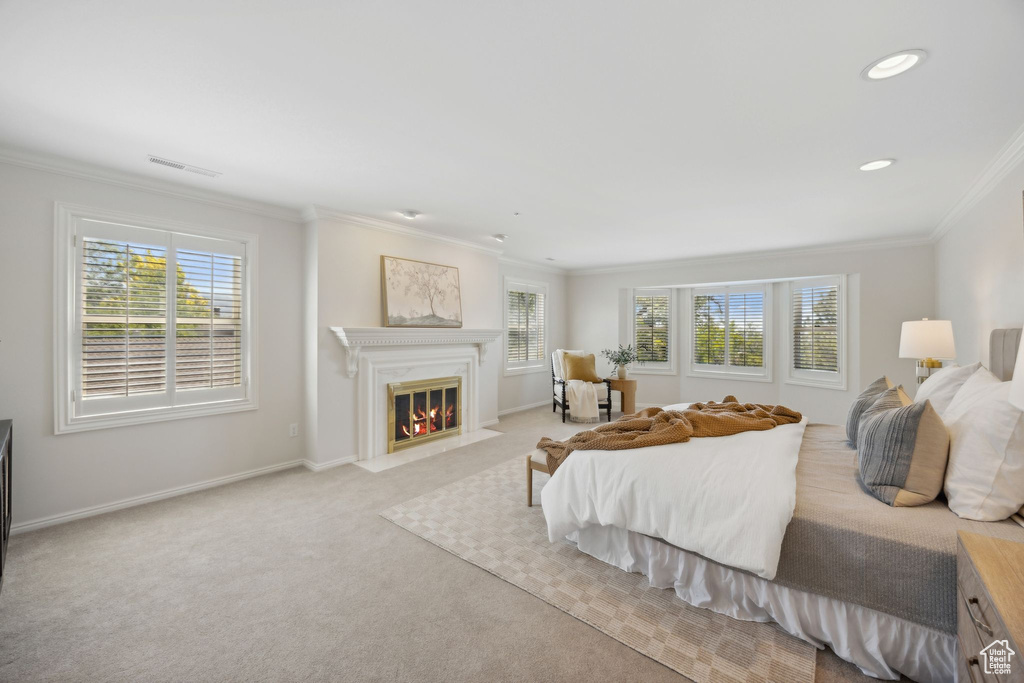 Bedroom with multiple windows, light carpet, and crown molding