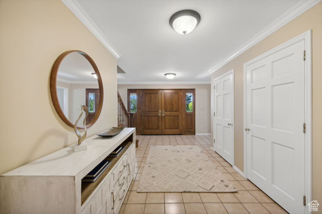 Foyer entrance with light tile patterned flooring and ornamental molding