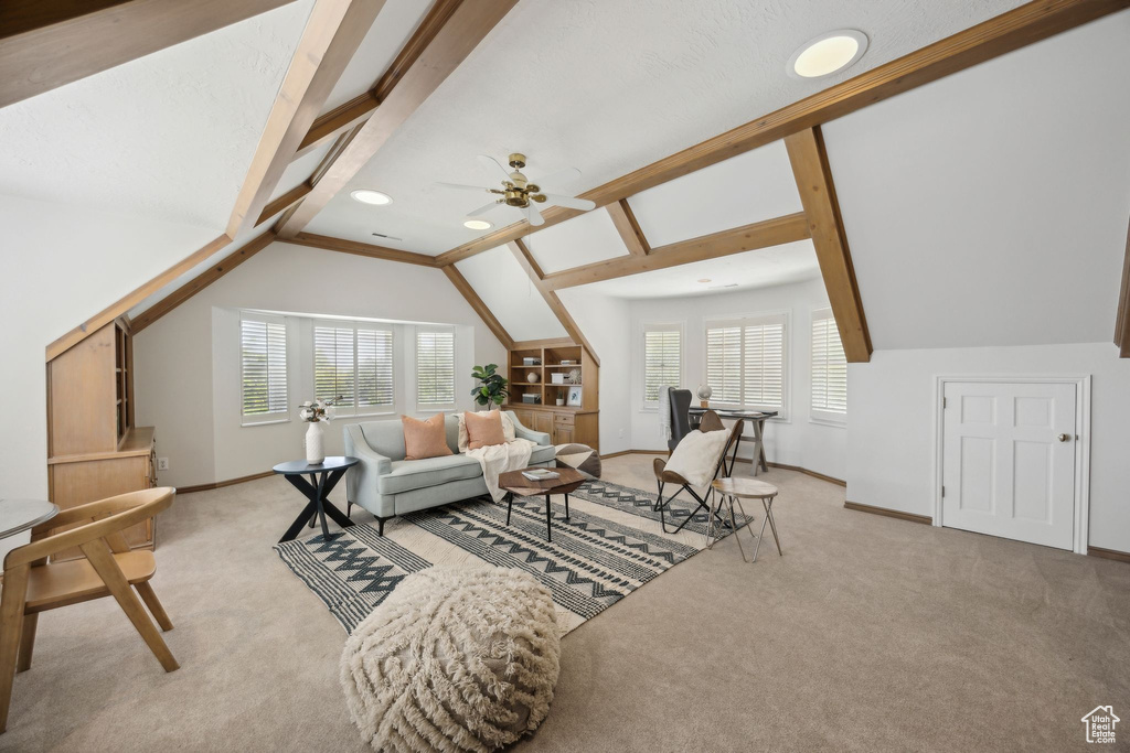 Carpeted living room featuring vaulted ceiling, ceiling fan, and a wealth of natural light