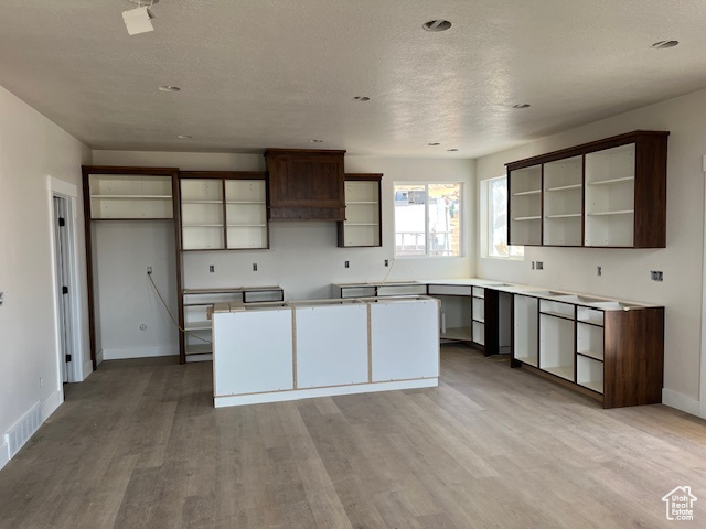 Kitchen with a center island, light hardwood / wood-style floors, and dark brown cabinets