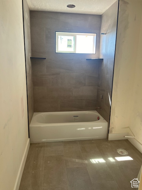 Bathroom featuring tile patterned floors, tiled shower / bath, and a textured ceiling