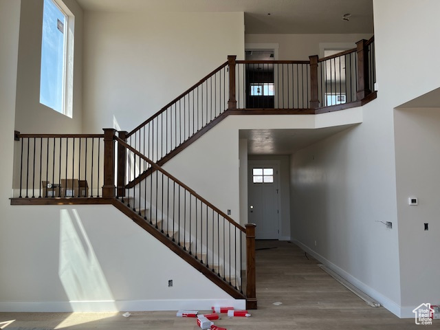 Stairway with light hardwood / wood-style floors and a high ceiling