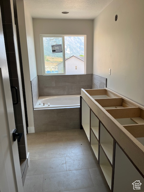 Bathroom with separate shower and tub, tile patterned floors, and a textured ceiling