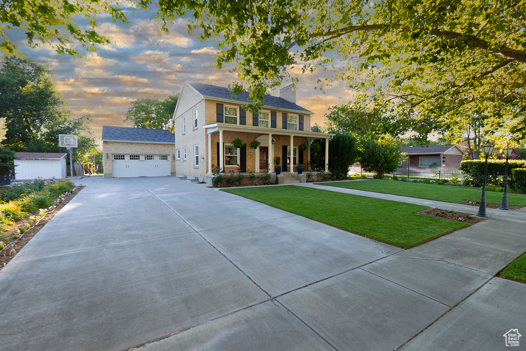 Colonial-style house with a porch, a garage, and a lawn