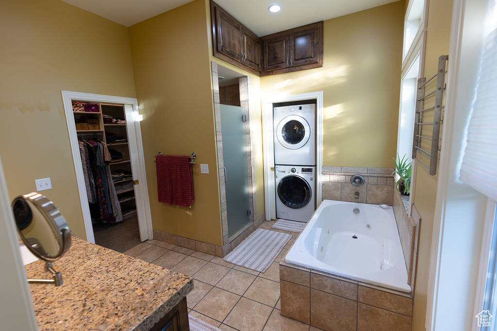 Bathroom featuring independent shower and bath, stacked washer and clothes dryer, and tile patterned flooring