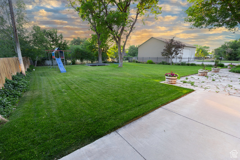 Yard at dusk featuring a playground and a patio area